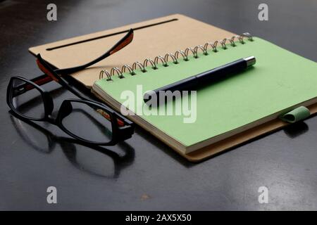 Foto eines Notebooks, Stifts und Brillen auf einem Tisch Stockfoto