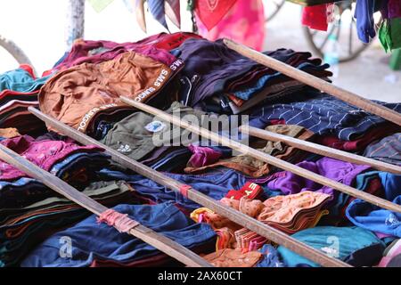 Nahaufnahme von mehrfarbigen Männern und Frauen unter Verschleiß im Straßengeschäft auf dem Markt mit langem Holzstab auf Tüchern, Straßenmarkt auf der Straße Stockfoto