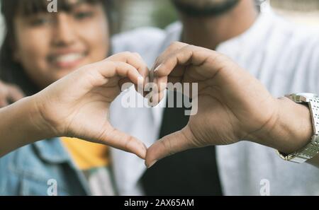 Ein Paar liebt es, Herz mit den Händen zu zeigen - Konzept der glücklichen Paarbeziehung und Zusammengehörigkeit Stockfoto
