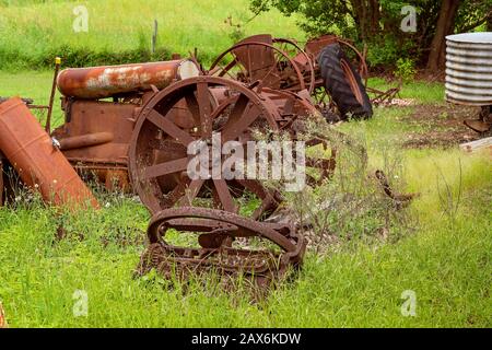 Alte verrostete Landmaschinen aus vergangener Zeit, die auf einem überwucherten Feld liegen Stockfoto