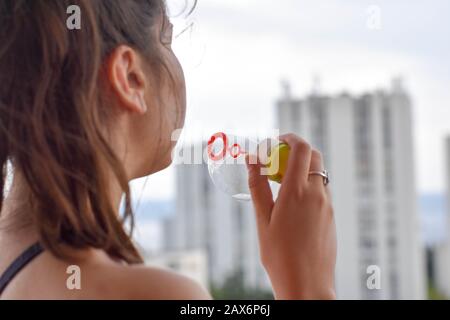 Glückliche schöne Frau, die Seifenblasen im Freien/konzeptionelles Bild der Kindheit bläst - Bild Stockfoto