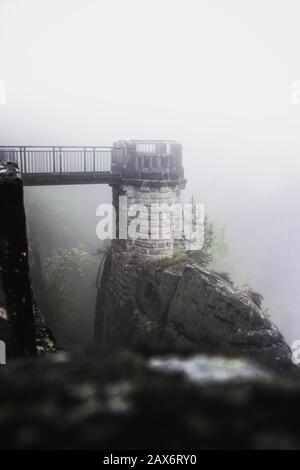 Winziger Turm, der im Nebel auf dem Basteigebiet in Sachsen durch Holzbrücke mit der Basteibrücke verbunden ist Stockfoto