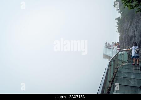 Zhangjiajie, China - August 2019: Touristen, die auf einem schmalen Glasweg im Tianmenshan Naturpark laufen Stockfoto