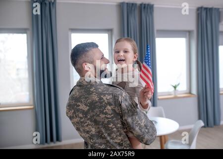 Papa, der eine kleine Tochter mit amerikanischer Flagge hält. Stockfoto