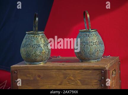 Zwei Mittelaltertöpfe, die auf Holzkiste vor rotem und blauem Stoff stehen Stockfoto