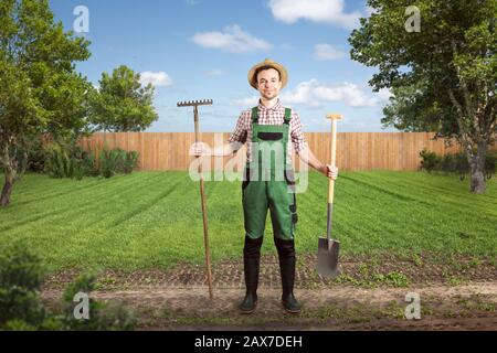 Lächelnder Gärtner bereit zur Arbeit in einem grünen Hinterhof Stockfoto
