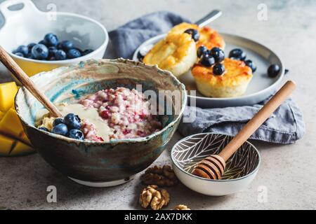 Frühstücksshintergrund. Haferbrei, Käsekuchen mit Beeren und Früchten auf dunklem Hintergrund. Stockfoto