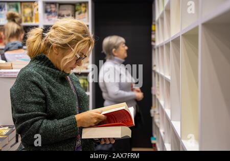 Katowice, Polen - 6. Bis 8. Dezember 2019: Frau, die während der Schlesischen Buchmesse 2019 in Katowice im Internationalen Kongresszentrum nach Büchern sucht. Stockfoto