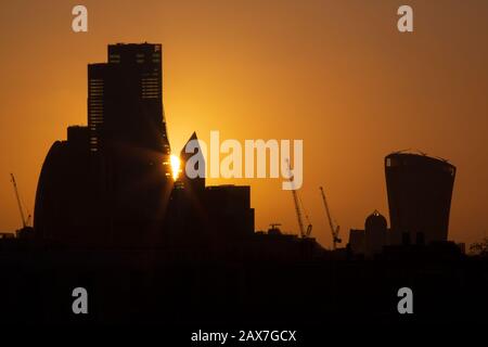 London. Februar 2020. Wetter in Großbritannien: Hinter der Skyline der City of London, Silhouetten von Wolkenkratzern und Baukränen, steigt die Sonne. Kredit: Thamesfleet/Alamy Live News Stockfoto