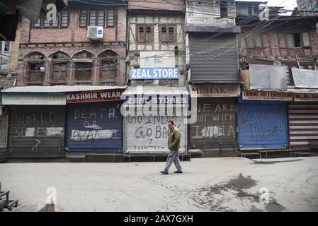 Ein Kaschmiri-Mann läuft während der Abschaltung in Srinagar an geschlossenen Geschäften vorbei.Es Wurden In einigen Teilen von Srinagar Beschränkungen für die Bewegung von Fahrzeugen als Jammu Kashmir Liberation Front (JKLF) auferlegt, eine Separatistengruppe im Tal forderte einen Streik zum Gedenken an den Todestag des JKLF-Gründers Maqbool Bhat. Maqbool wurde am 11. Februar 1984 von der indischen Regierung im Tihar-Gefängnis von Neu-Delhi gehängt. Die Forderung der JKLF nach einem Streik und sie ist die erste von jeder Separatistengruppe seit dem 5. August 2019, als die von der BJP geführte Zentralregierung Artikel 370 der Verfassung zurücknahm. Inzwischen waren Internetdienste als Stockfoto