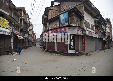 Eine Kaschmiri-Frau spaziert während der Abschaltung in Srinagar vor geschlossenen Geschäften. In einigen Teilen von Srinagar wurden Einschränkungen für die Bewegung von Fahrzeugen als Jammu Kashmir Liberation Front (JKLF) auferlegt, Eine Separatistengruppe im Tal forderte einen Streik zur Erinnerung an das Todesjahr des JKLF-Gründers Maqbool Bhat. Maqbool wurde am 11. Februar 1984 von der indischen Regierung im Tihar-Gefängnis von Neu-Delhi gehängt. Die Forderung der JKLF nach einem Streik und sie ist die erste von jeder Separatistengruppe seit dem 5. August 2019, als die von der BJP geführte Zentralregierung Artikel 370 der Verfassung zurücknahm. Internetdienste Stockfoto