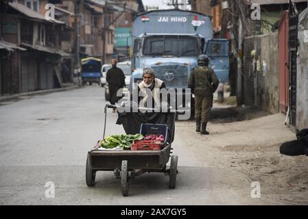 Ein Kashmiri-Händler bewegt seinen Gemüsewagen während der Abschaltung in Srinagar an einem gepanzerten Fahrzeug vorbei.Es Wurden In einigen Teilen von Srinagar Beschränkungen für die Bewegung von Fahrzeugen als Jammu Kashmir Liberation Front (JKLF) auferlegt, Eine Separatistengruppe im Tal forderte einen Streik zur Erinnerung an das Todesjahr des JKLF-Gründers Maqbool Bhat. Maqbool wurde am 11. Februar 1984 von der indischen Regierung im Tihar-Gefängnis von Neu-Delhi gehängt. Die Forderung der JKLF nach einem Streik und sie ist die erste von jeder Separatistengruppe seit dem 5. August 2019, als die von der BJP geführte Zentralregierung Artikel 370 der Verfassung zurücknahm. In Der Zwischenzeit Stockfoto