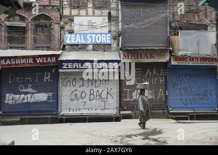 Ein Kashmiri-Händler läuft während der Abschaltung in Srinagar an geschlossenen Geschäften vorbei.Es Wurden In einigen Teilen von Srinagar Beschränkungen für die Bewegung von Fahrzeugen auferlegt, da Jammu Kashmir Liberation Front (JKLF), eine Separatistengruppe im Tal einen Streik zum Gedenken an den Todestag des JKLF-Gründers Maqbool Bhat forderte. Maqbool wurde am 11. Februar 1984 von der indischen Regierung im Tihar-Gefängnis von Neu-Delhi gehängt. Die Forderung der JKLF nach einem Streik und sie ist die erste von jeder Separatistengruppe seit dem 5. August 2019, als die von der BJP geführte Zentralregierung Artikel 370 der Verfassung zurücknahm. Inzwischen waren Internetdienste Stockfoto