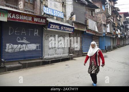 Eine Kaschmiri-Frau spaziert während der Abschaltung in Srinagar vor geschlossenen Geschäften. In einigen Teilen von Srinagar wurden Einschränkungen für die Bewegung von Fahrzeugen als Jammu Kashmir Liberation Front (JKLF) auferlegt, Eine Separatistengruppe im Tal forderte einen Streik zur Erinnerung an das Todesjahr des JKLF-Gründers Maqbool Bhat. Maqbool wurde am 11. Februar 1984 von der indischen Regierung im Tihar-Gefängnis von Neu-Delhi gehängt. Die Forderung der JKLF nach einem Streik und sie ist die erste von jeder Separatistengruppe seit dem 5. August 2019, als die von der BJP geführte Zentralregierung Artikel 370 der Verfassung zurücknahm. Internetdienste Stockfoto