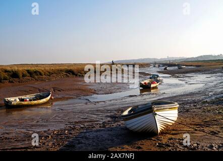 Blick auf einen Tidal Creek mit kleinen Booten bei Niedrigwasser im Winter an der Küste von North Norfolk bei Morston, Norfolk, England, Großbritannien, Europa. Stockfoto