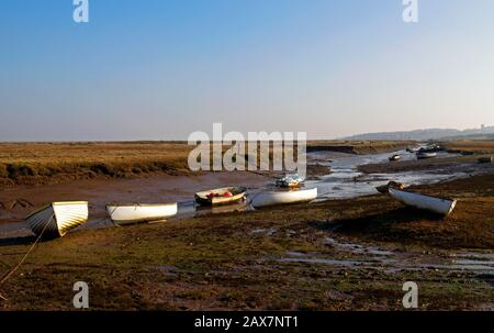 Blick auf einen Tidal Creek mit kleinen Booten bei Niedrigwasser im Winter an der Küste von North Norfolk bei Morston, Norfolk, England, Großbritannien, Europa. Stockfoto