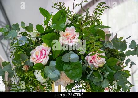 Wunderschöner Blumenstrauß aus künstlichen rosafarbenen Rosen und grünen Blättern Stockfoto