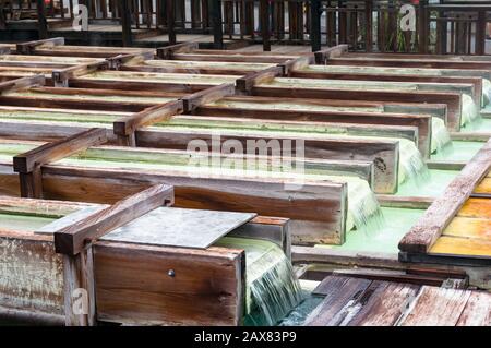 Yubatake Warmfederinfrastruktur mit Holzkisten mit fließendem Mineralwasser. Kusatsu, Japan Stockfoto