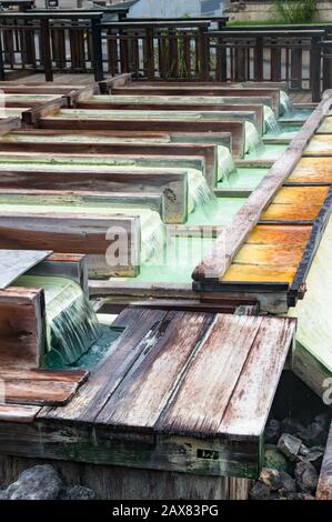 Mineralwasser, das über Holzkisten von Yubatake Onsen fließt, heiße Quelle. Kusatsu, Japan Stockfoto