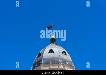 Kuppel des Royal Exhibition Building mit australischer Flagge vor blauem Himmel auf dem Hintergrund Stockfoto