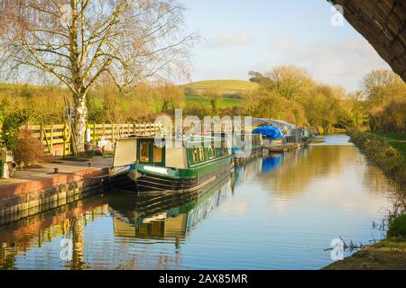 Eine ruhige sonnige Landschaft Anfang Januar, die den Kennet- und Avon-Kanal und schmale Boote zeigt, die auf Honeystreet in der Vale von Pewsey in Wiltshire England in Großbritannien gefestigt sind Stockfoto