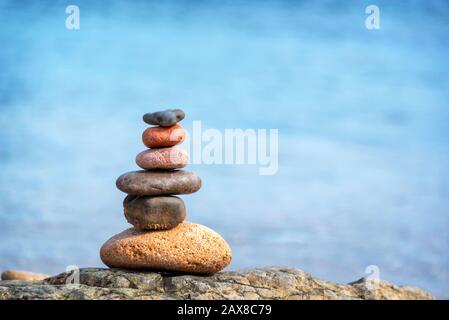 Kieselhaufen an einem Strand, blauer Wasserhintergrund Stockfoto