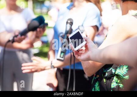 Öffentliche Persönlichkeit im Gespräch mit den Medien, Reporter halten Mikrofone auf der Pressekonferenz Stockfoto