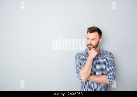 Konzentrierter, nachdenklicher Geschäftsmann, der Kinn auf grauem Hintergrund anfasst Stockfoto