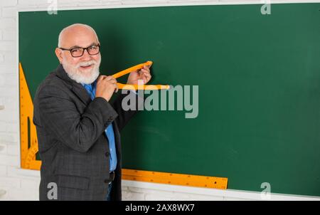 Lehrer des Obermannes verwenden Kompasswerkzeug. Bärtiger Tutor zeichnet mit Kompass auf der Tafel. Zurück zur Schule. Mathematische Grafikwerkzeuge Konzept. Für Wissen. Mathe für gute Ergebnisse untersuchen. Speicherplatz kopieren. Stockfoto