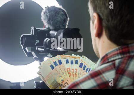 Männlicher Vlogger zählt Geld aus vlogging Stockfoto