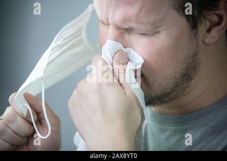 Der Mensch wird von Virus/Mann angesteckt, der niest. Stockfoto