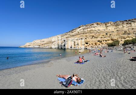 Matala, Griechenland - 07. Oktober 2018: Nicht identifizierte Menschen am Strand mit alten Gräbern auf dem Hügel Stockfoto