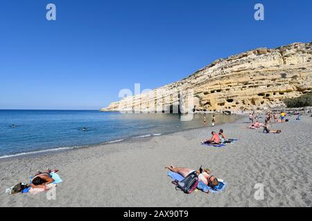 Matala, Griechenland - 07. Oktober 2018: Nicht identifizierte Menschen am Strand mit alten Gräbern auf dem Hügel Stockfoto