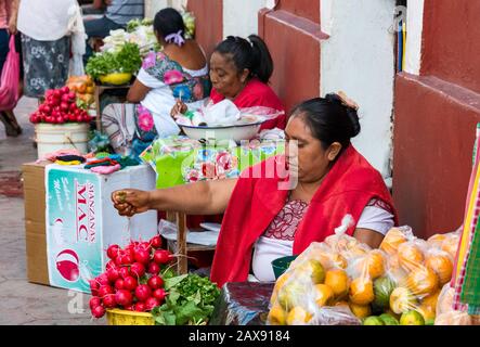 Frau, die Gemüse und Obst verkauft, in der Calle 44 in Valladolid, Bundesstaat Yucatan, Mexiko mit Huipil, traditionellem, handverstricktem Maya-Kleid trägt Stockfoto