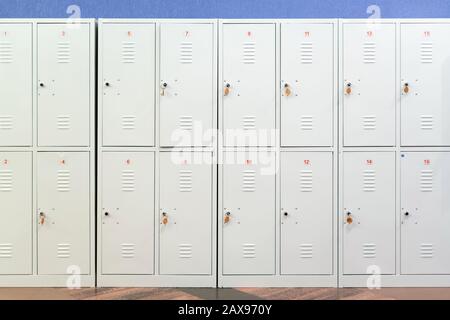 Eine Reihe graumetallener Schulschließfächer mit Schlüsseln in den Türen. Stauraum im Flur der Bildungseinrichtung Stockfoto