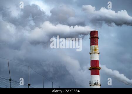 Dunkle giftige Rauchwolken, die aus dem Fabrikschornstein kommen. Luftverschmutzung und Erderwärmung durch altes Industriekraftwerk Stockfoto