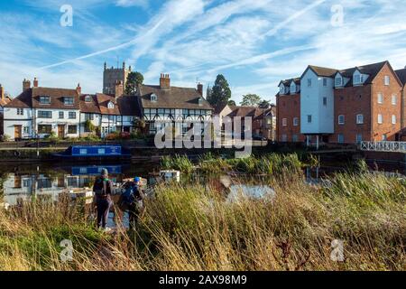 24. Oktober 2018 - Tewkesbury, Großbritannien: Zwei Personen stehen mit Angelausrüstung vor einer malerischen Gruppe von Hütten, die sich im ruhigen Fluss Avon in der Nähe von Abbey Mill in der Stadt Tewkesbury, Gloucestershire, Severn Vale, Großbritannien, spiegeln Stockfoto