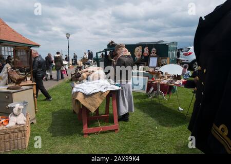 Leute, die alte Bettwäsche auf einem Stand auf dem jährlichen Brocante Antiquitätenmarkt auf Walmer Green, Deal, Kent, Großbritannien, betrachten Stockfoto