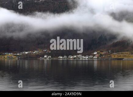 Blick auf das Dorf Ålvik an den Küsten des Hardanger Fjords, der Grafschaft Hordaland, Norwegens. Schöne traditionelle norwegische Landschaft. Nebeliger Berg, Wald, Woode Stockfoto