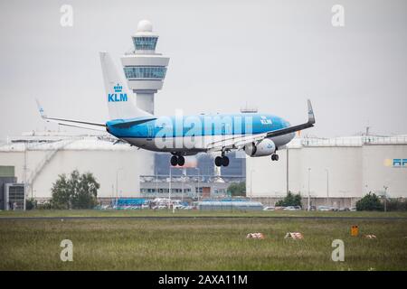 KLM Royal dutch Airline Boeing 737 landet auf dem Flughafen Schiphol Amsterdam, mit dem Kontrollturm im Hintergrund Stockfoto