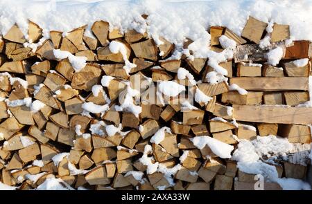 Brennholz schneiden Winterbrennstoff Holzstapel. Gestapeltes Winterbrennholz. Brennholz bedeckt mit Schnee in der Region Leningrad. Russland. Stockfoto