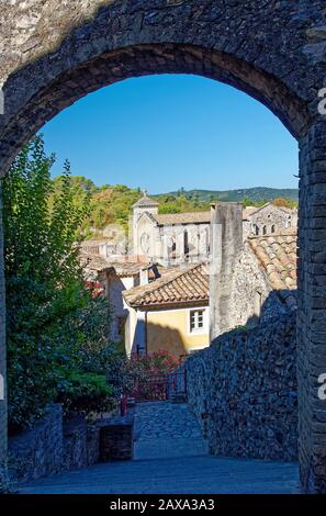 Blick auf die Stadt durch Steinbogen, alte Gebäude, Ziegeldächer, Kirche, steile Stufen, Hügel, Viviers, Frankreich; Sommer, vertikal Stockfoto