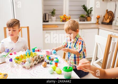 Zwei Jungen malen Ostereier in ihrer Küche Stockfoto