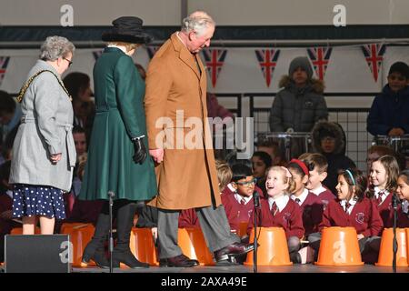 Der Prince of Wales und die Duchess of Cornwall interagieren mit Schulkindern auf der Bühne am Leicester Market vor der Enthüllung einer Gedenkplakette auf dem neuen Marktplatz. Stockfoto