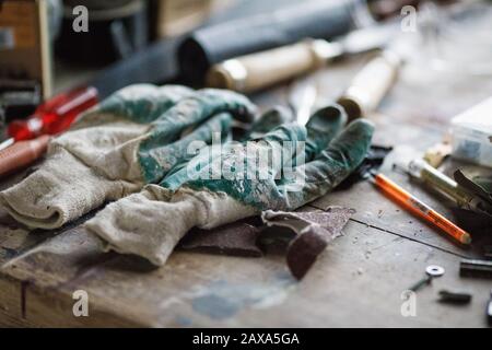 Arbeitshandschuhe an einem Werksarbeitsplatz Stockfoto