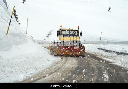 Vorderansicht des Schneepflugwagens bei der Arbeit an einem stürmischen Wintertag in den alpen. Stockfoto