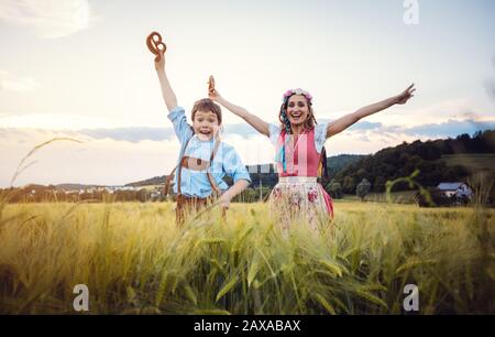 Fröhliche Mutter und Sohn in Bayern springen auf eine Wiese Stockfoto