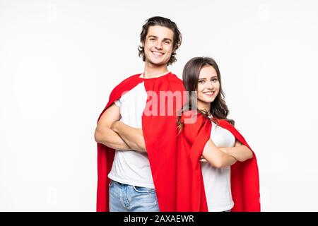 Super Paar in Masken und Umhang, die mit den Händen auf der Taille stehen und die Kamera auf weißem Hintergrund betrachten Stockfoto