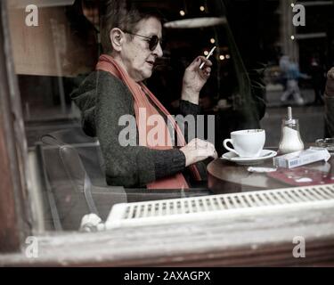 Belgrad, Serbien, 7. Februar 2020: Eine ältere Dame, die Kaffee und Zigaretten in einem der Cafés in der Innenstadt genießt Stockfoto