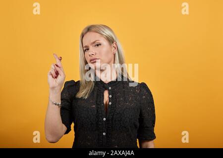 Die fokussierte Frau zeigt, dass die Daumen gequeren, alles wird gut sein, um viel Glück zu haben Stockfoto